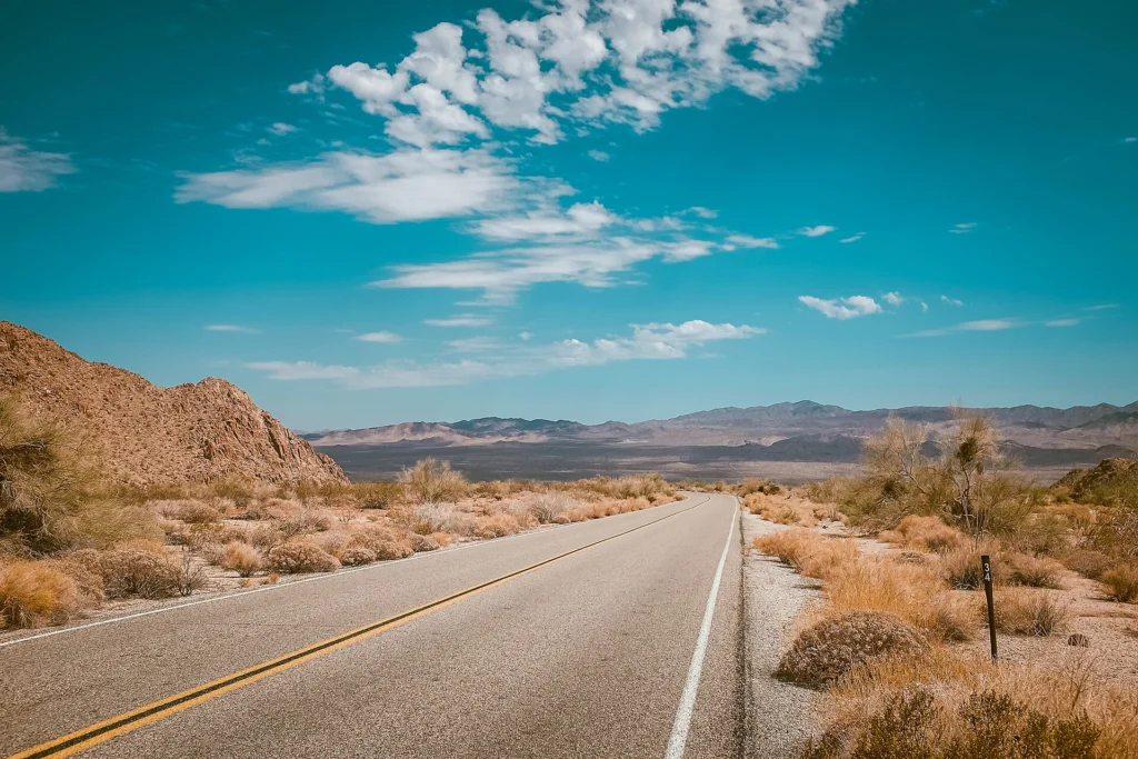 Desert highway running toward mountains under a clear blue sky