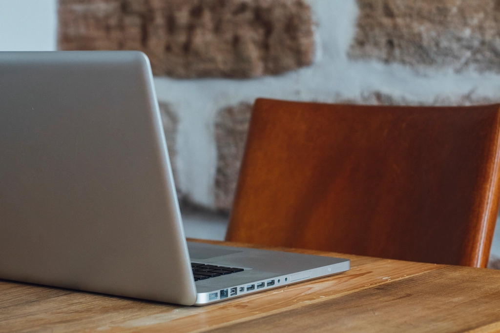 Silver laptop on a wooden table used while preparing AI shopping pages