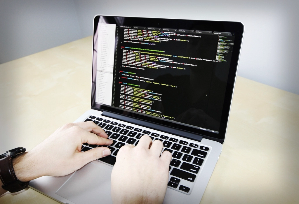 Integration: Developer typing code on a laptop at a light wooden desk