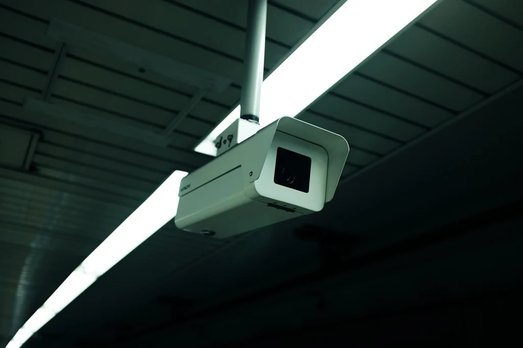 Surveillance camera mounted on a ceiling next to a fluorescent light