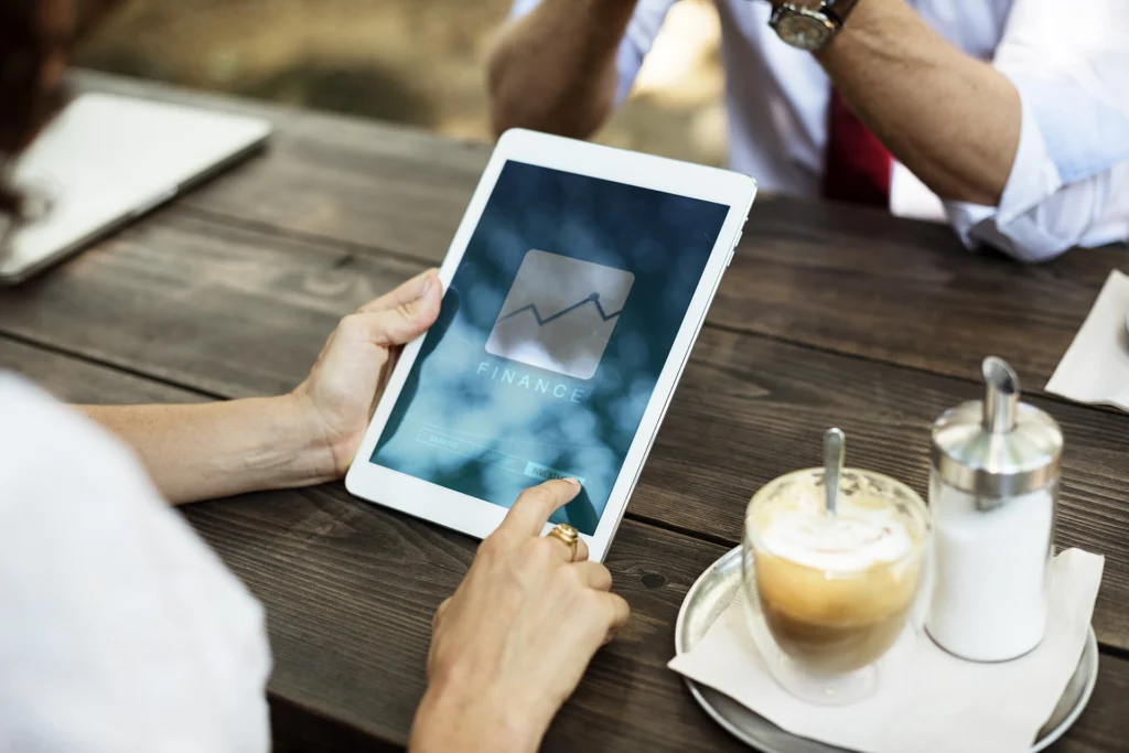 Hands holding a tablet with a growth chart during a meeting over coffee