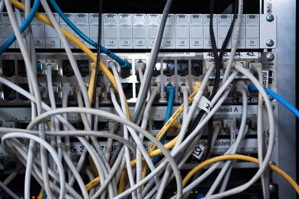 Network patch panel with many tangled cables plugged into numbered ports