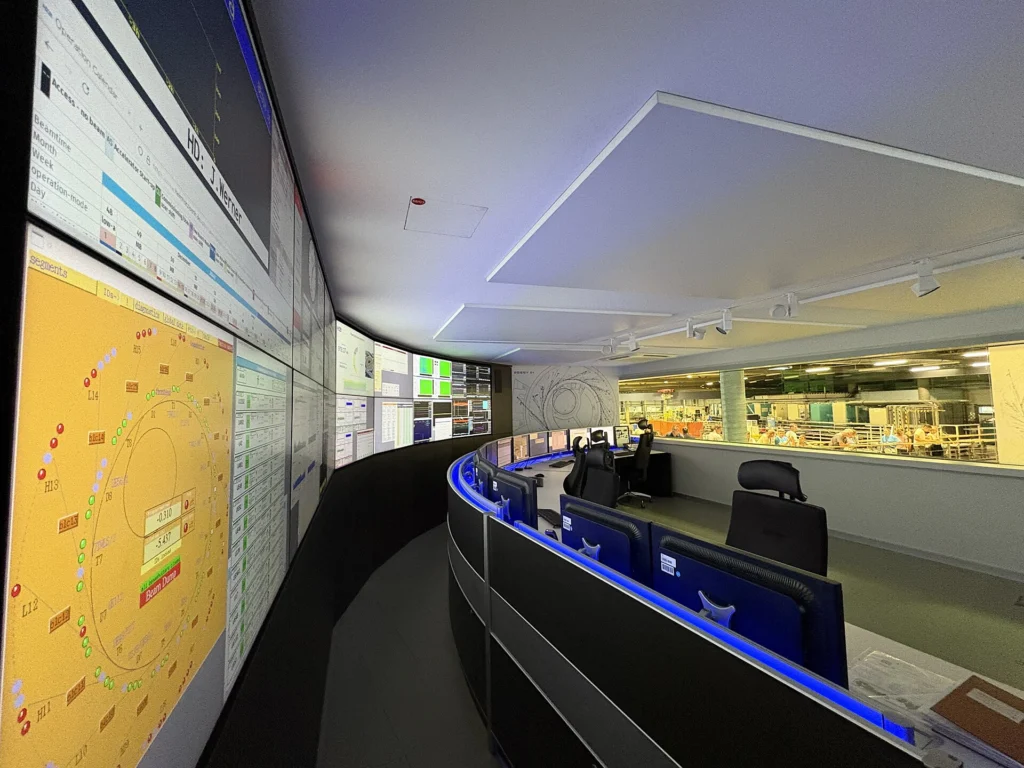 Control room with a curved wall of monitoring screens and operator desks
