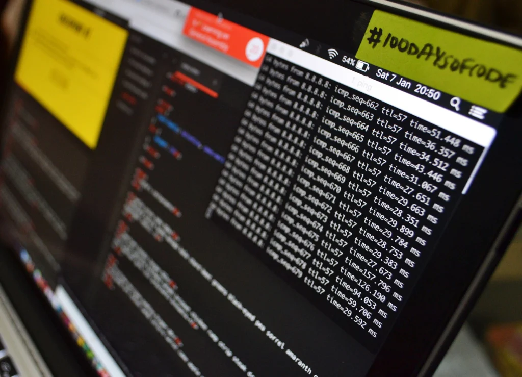 Laptop with a terminal window full of command output next to a code editor