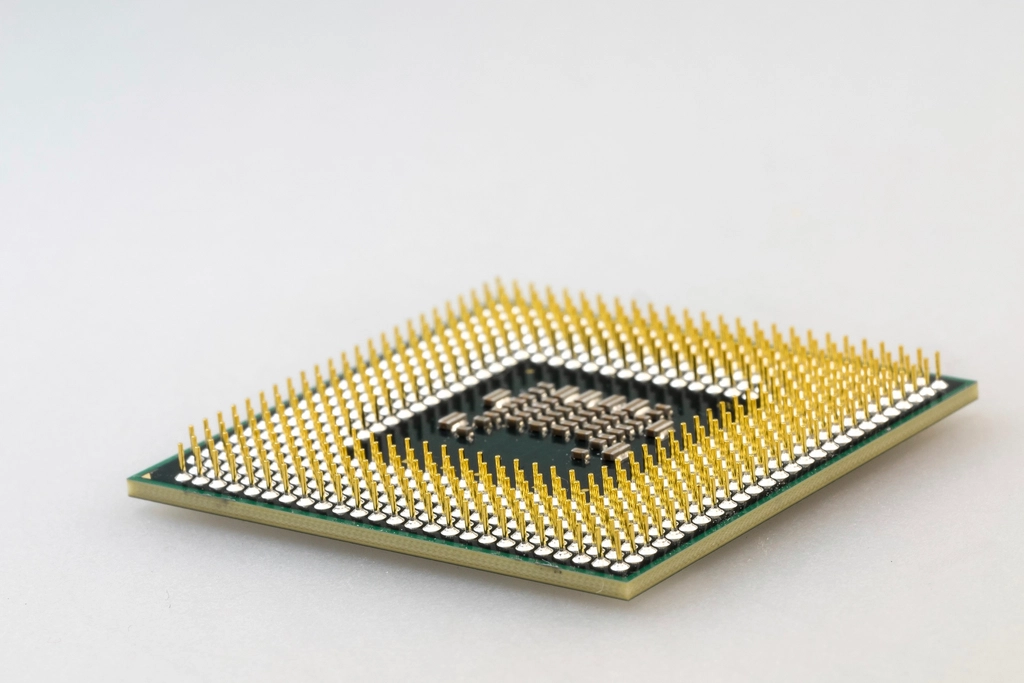 Close-up of a computer processor with gold pins on a white surface