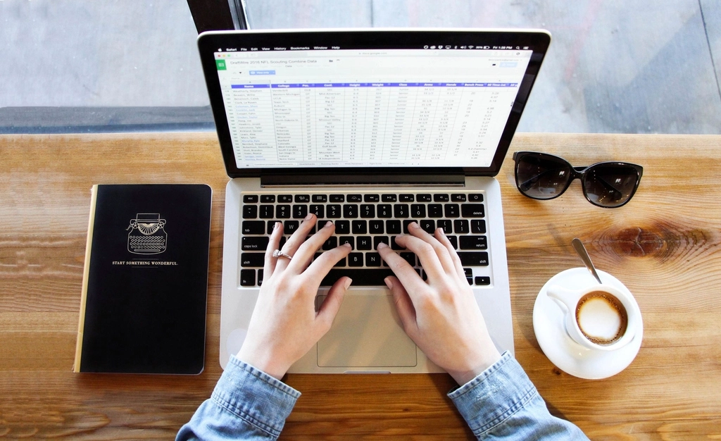 Hands typing on a laptop showing a spreadsheet of customer records
