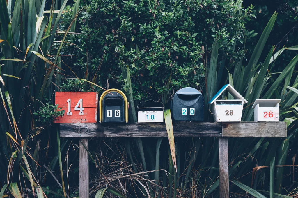 A row of small colorful mailboxes lined up on a wooden bench outdoors