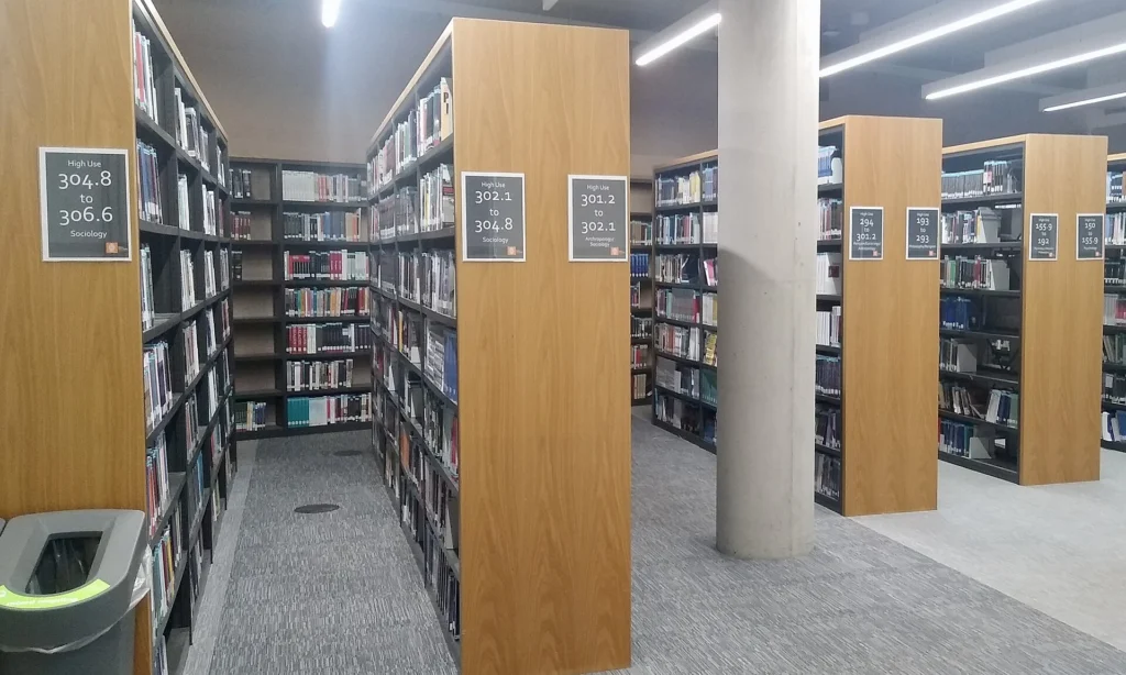 Library aisles with labelled shelf ends guiding readers to book categories