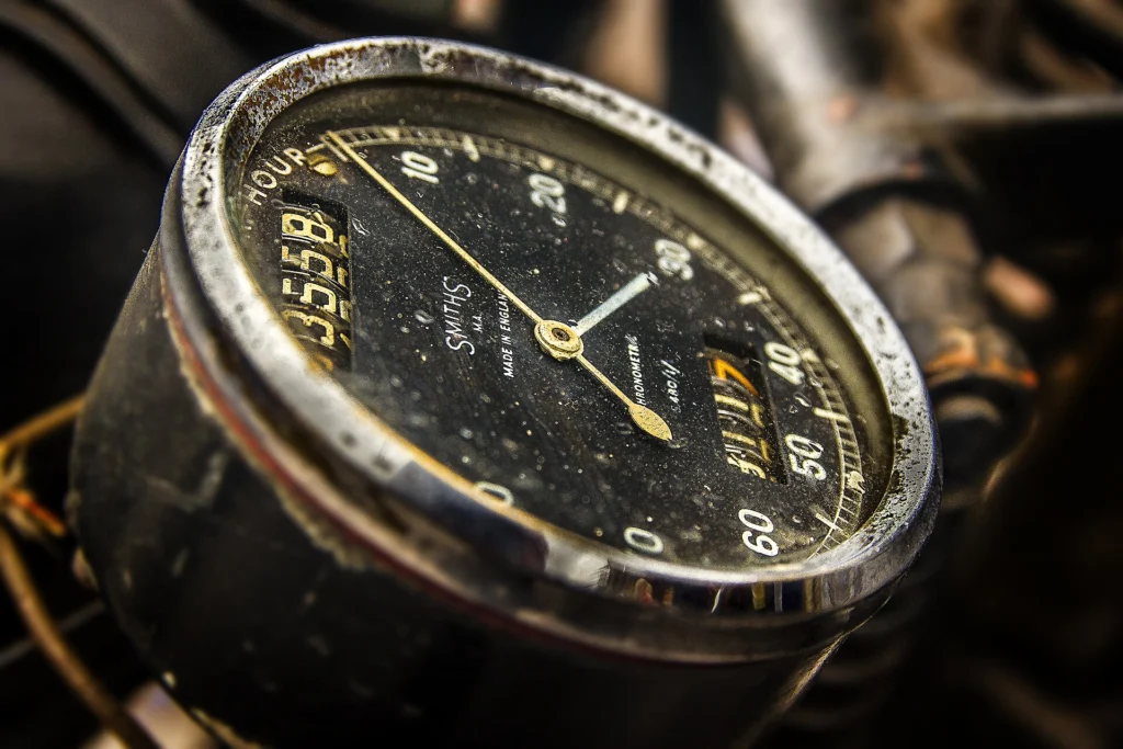 Close-up of a vintage speedometer gauge with a black dial