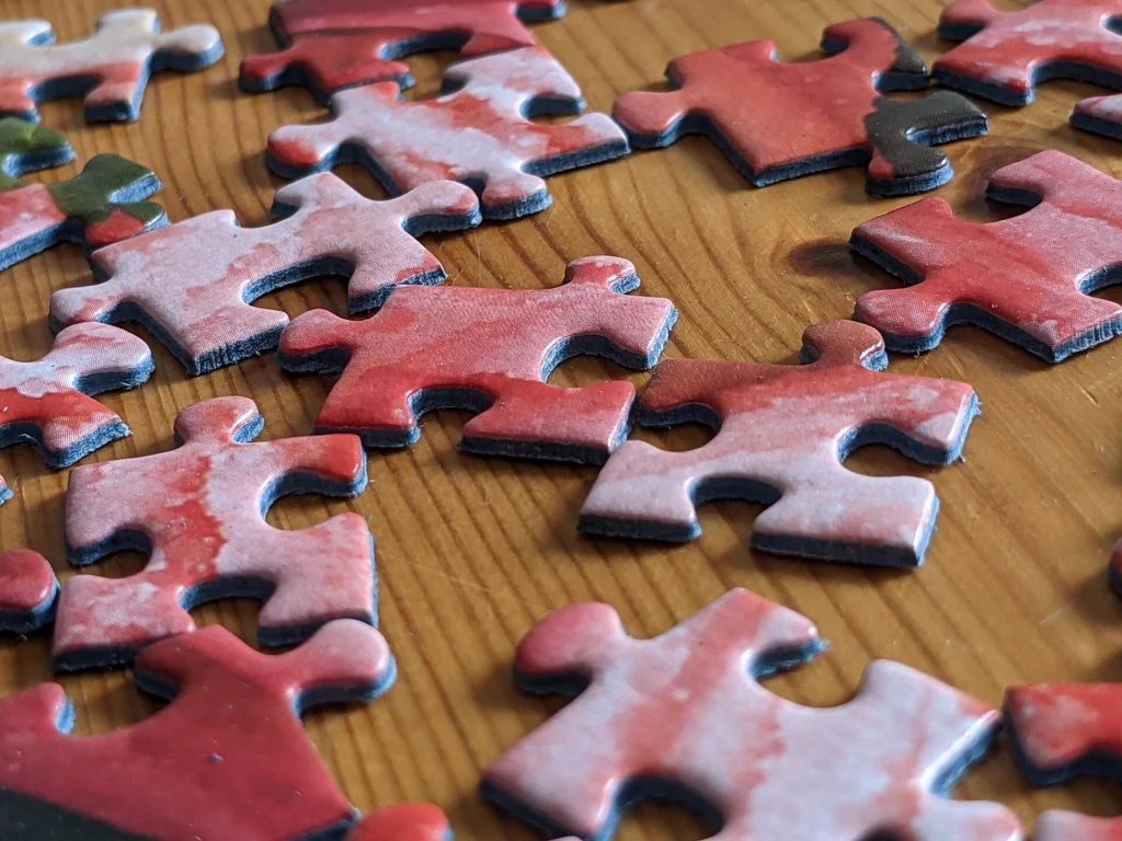 Sharding: Red jigsaw puzzle pieces spread out on a wooden table