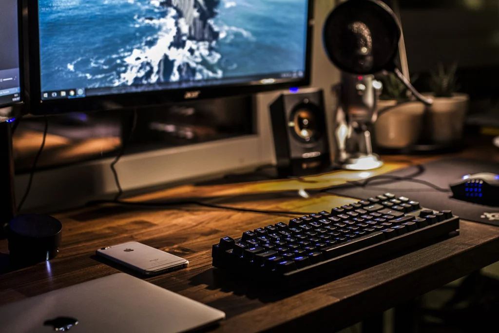 Developer workstation with a monitor, backlit keyboard and laptop on a wooden desk