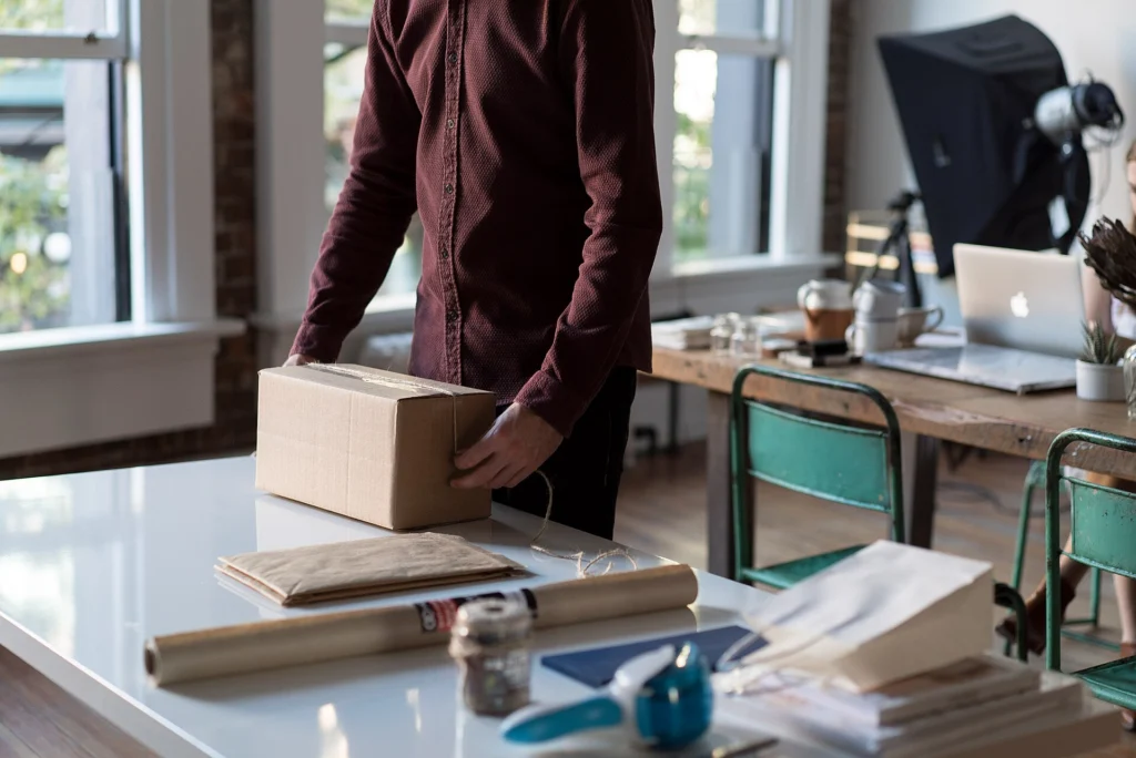 Lazy Loading: Person packing a small cardboard parcel on a bright office desk