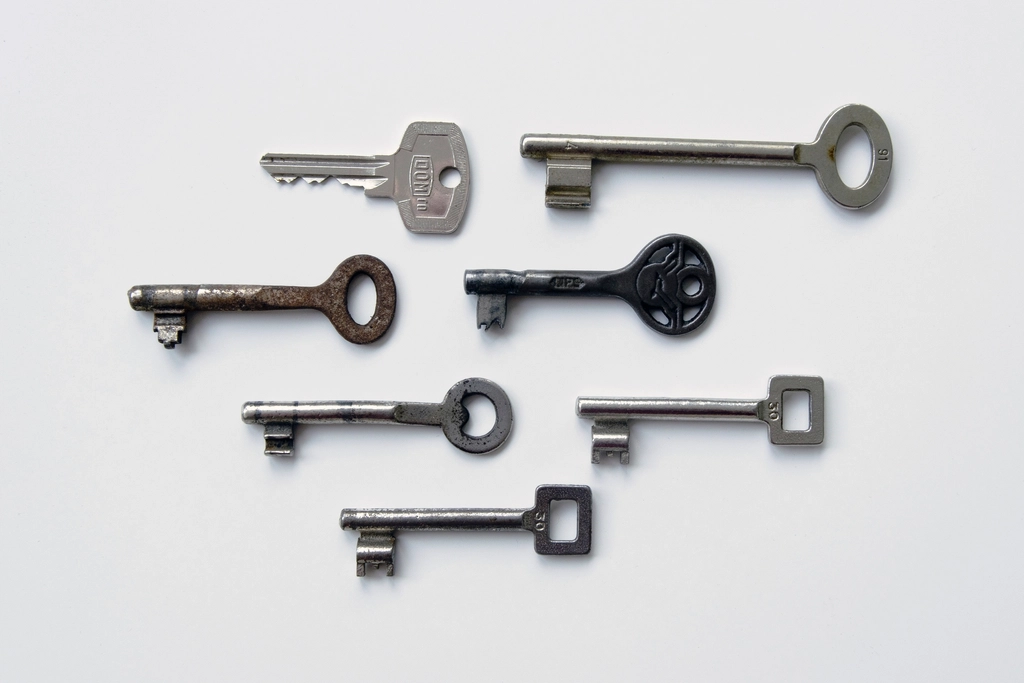 Collection of old metal door keys arranged on a white background