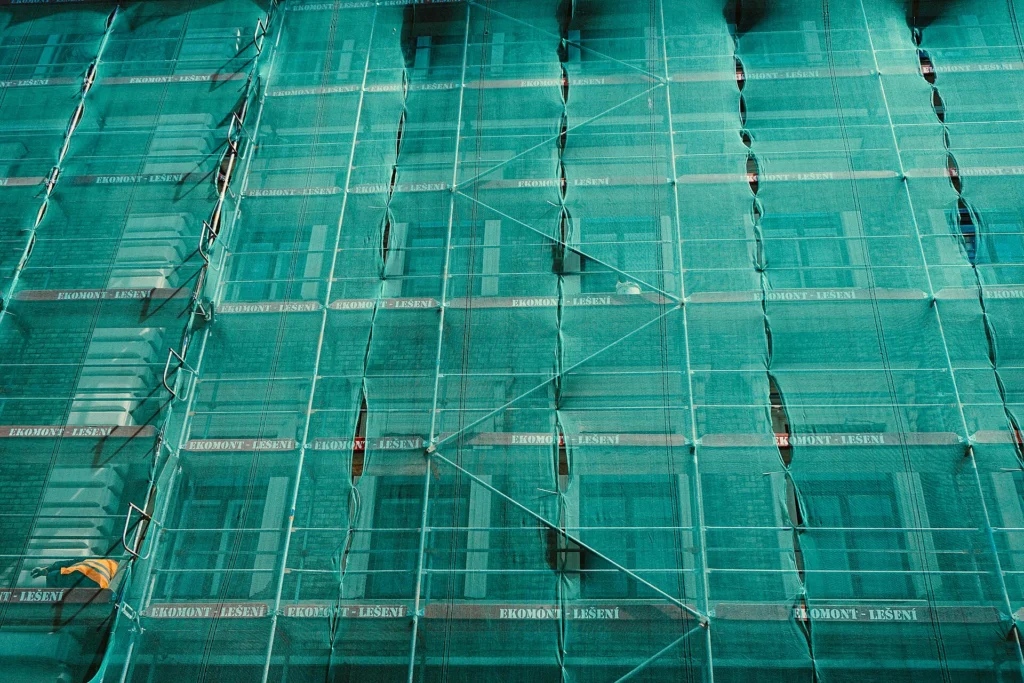 Modernization: Building facade covered in green mesh scaffolding during renovation work
