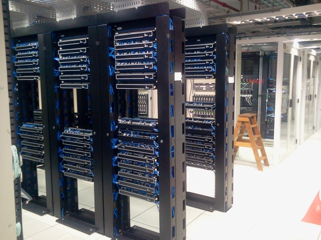 Rows of black server racks with blue network cables in a server room