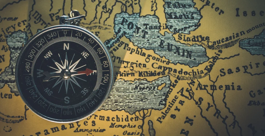 Top view of a vintage compass lying on an old paper map