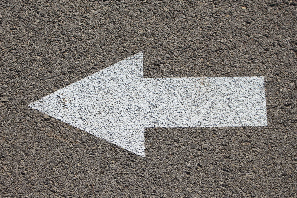 White arrow painted on asphalt pointing back to the left