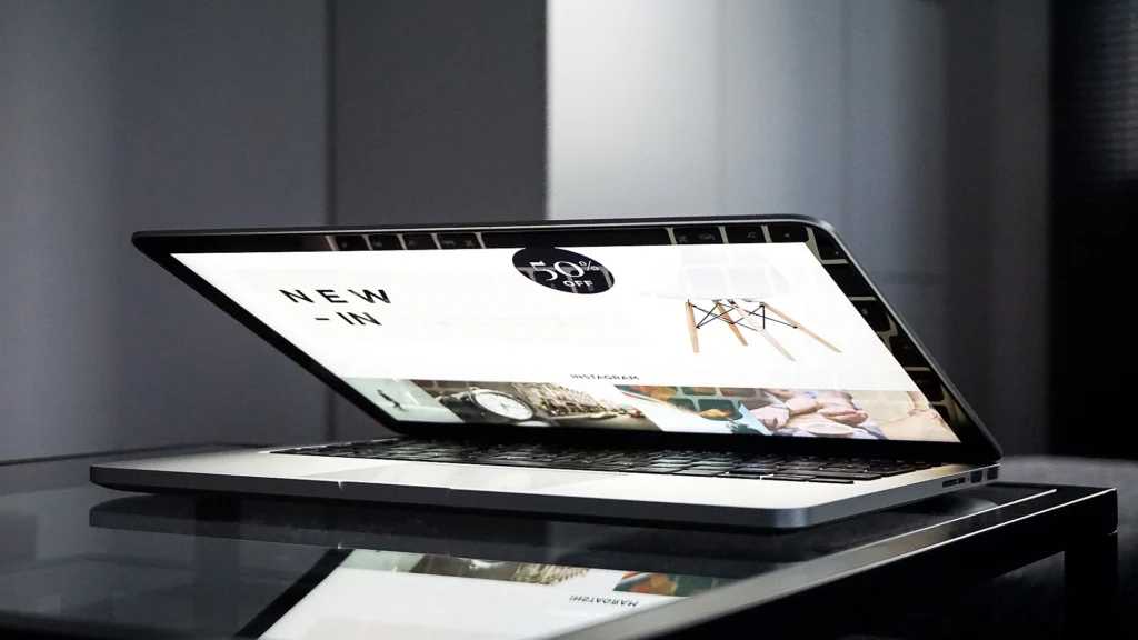 Development Services: Laptop on a glass desk displaying the homepage of a modern online store