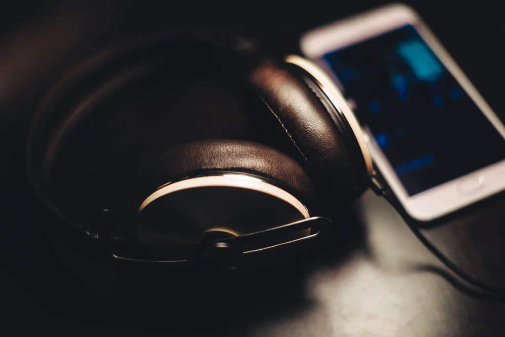 White smartphone beside black headphones on a dark table