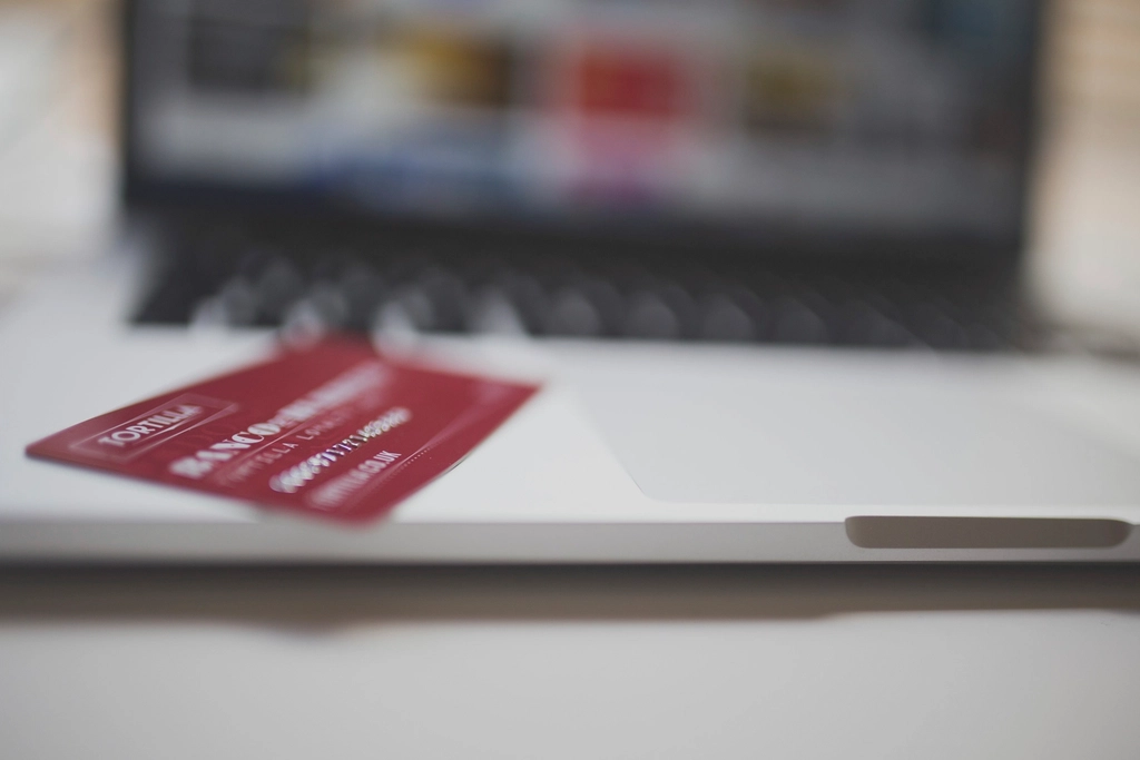 Red payment card lying on a laptop with a blurred online store in the background