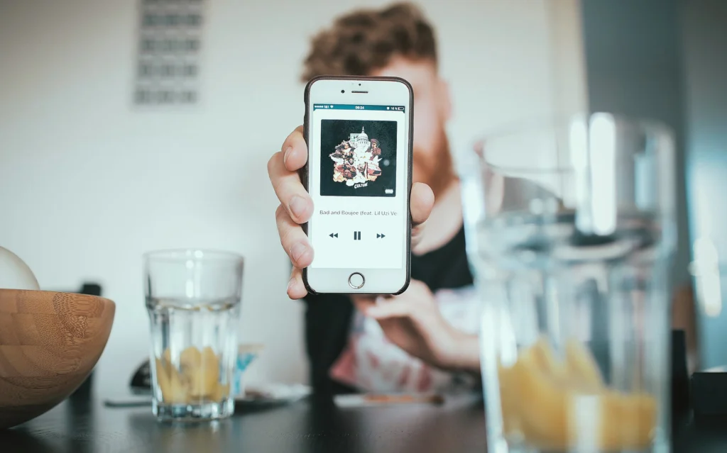 PWA: Hand holding a smartphone with a media player app open on screen