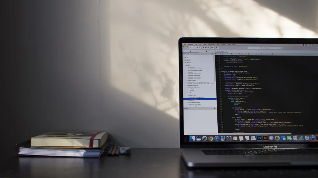 Message: Laptop showing source code on a desk next to a stack of books