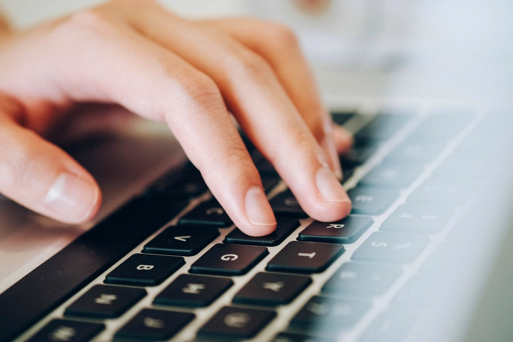 Hands typing on a laptop keyboard in close-up