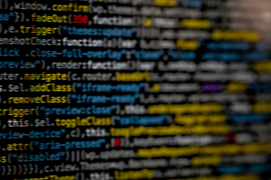Testing: Close-up of blurred source code on a dark computer screen
