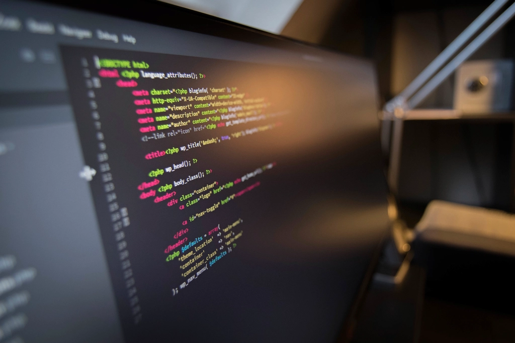 Close-up of colorful source code on a computer monitor in a dark room