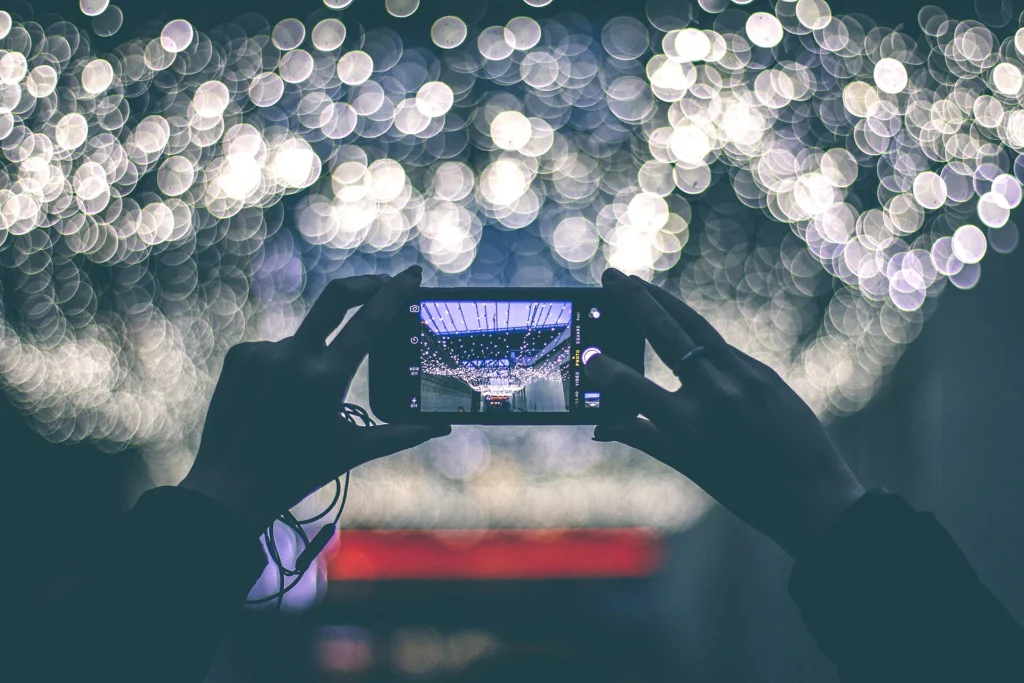 Two hands holding up a smartphone in front of blurred glowing city lights