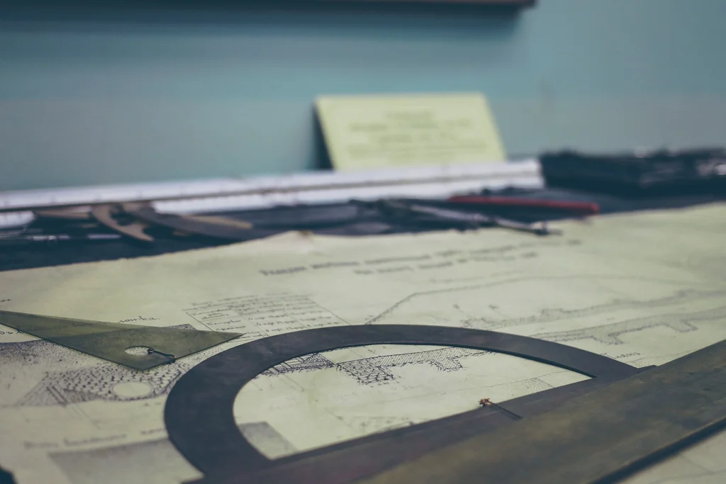 Architectural drawings and drafting tools spread across a work table