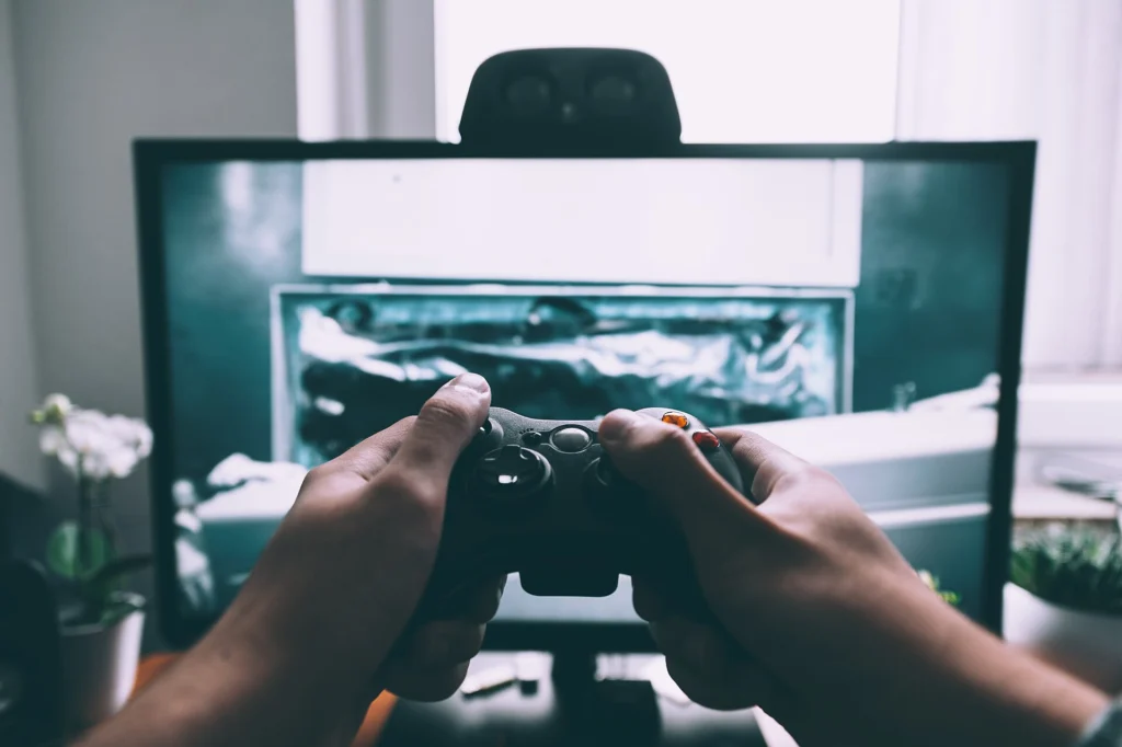 Hands holding a game controller in front of a screen during play